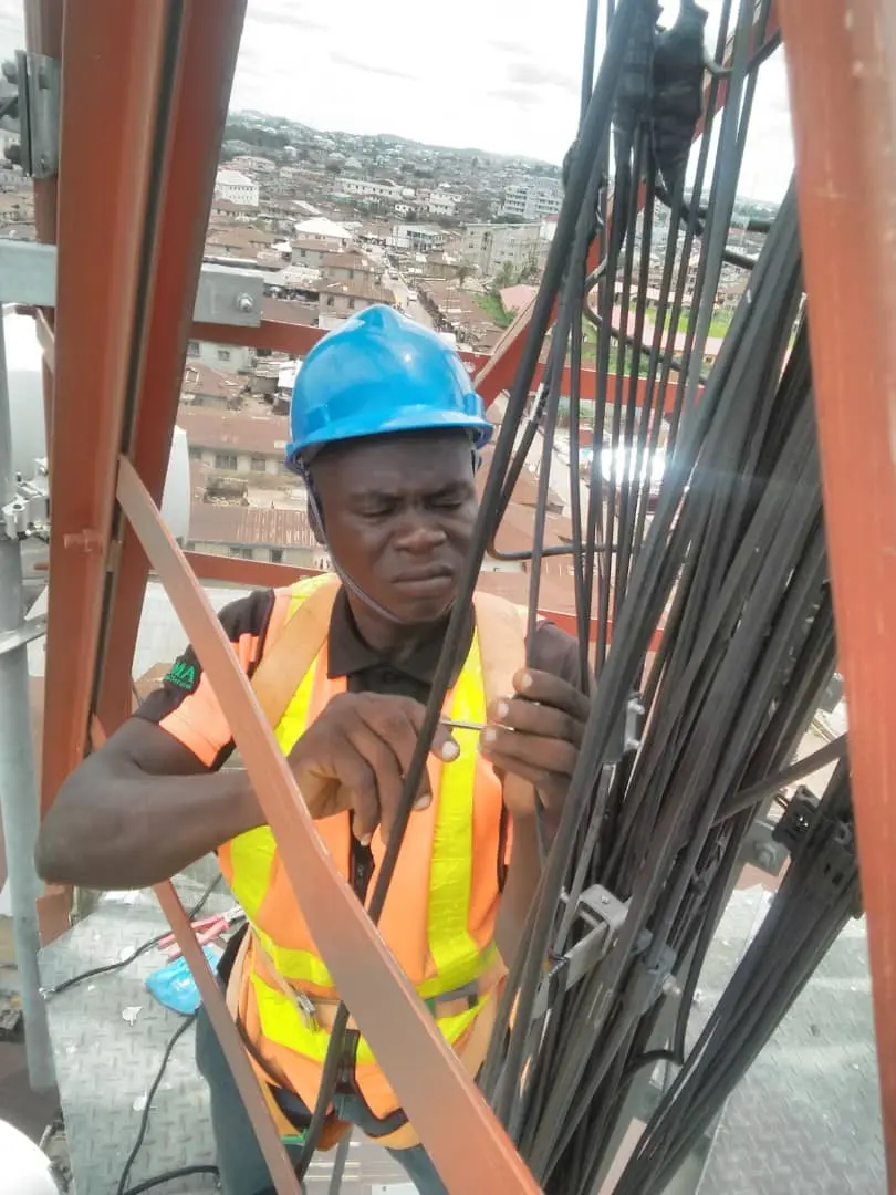 Field technician installing bundled cables on a telecommunications structure